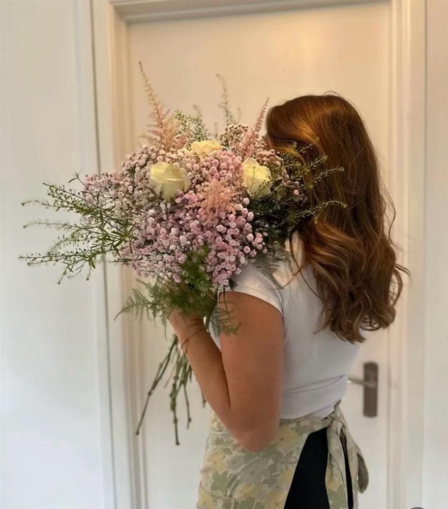 Soft pink and cream bouquet held by a florist