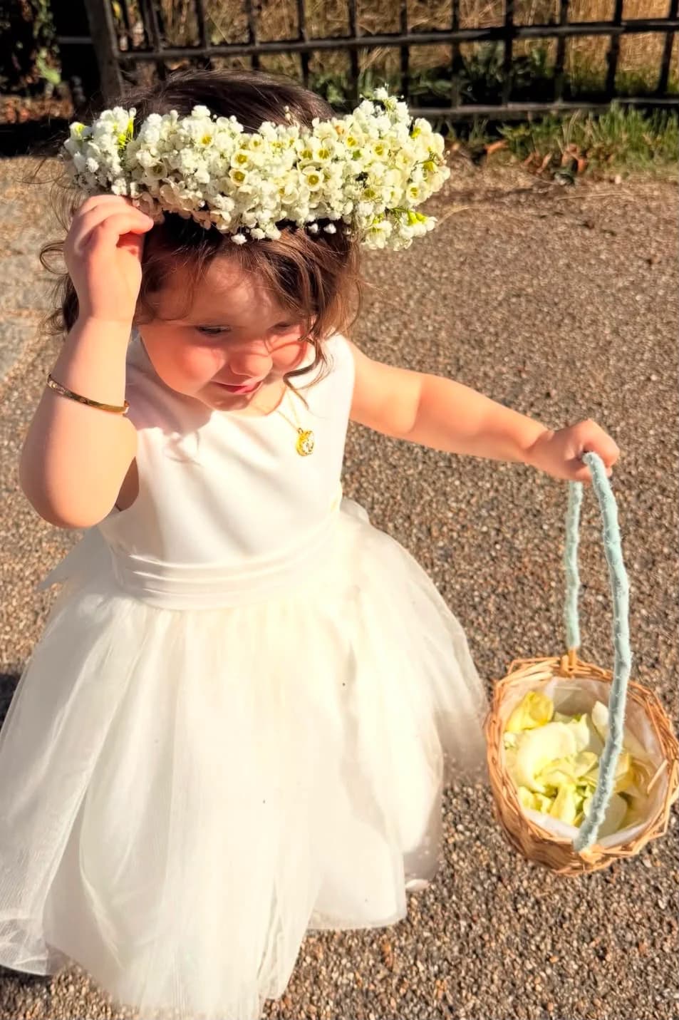 A flower girl wearing a delicate white flower crown and carrying a basket of petals