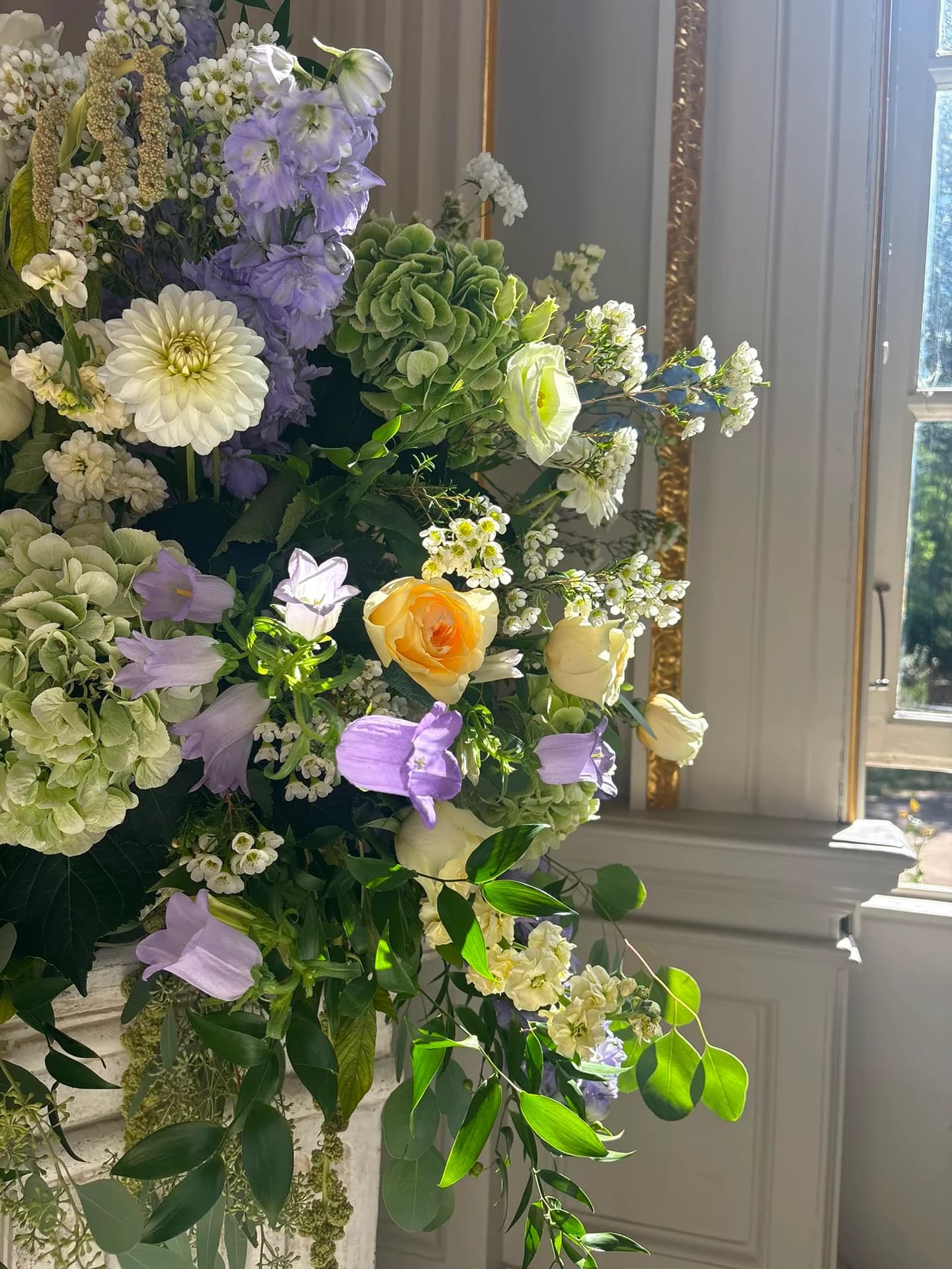 Green hydrangeas, white dahlias, pale yellow roses and lilac flowers in a wedding pedestal arrangement